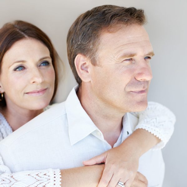 Portrait of beautiful woman embracing man from behind at home